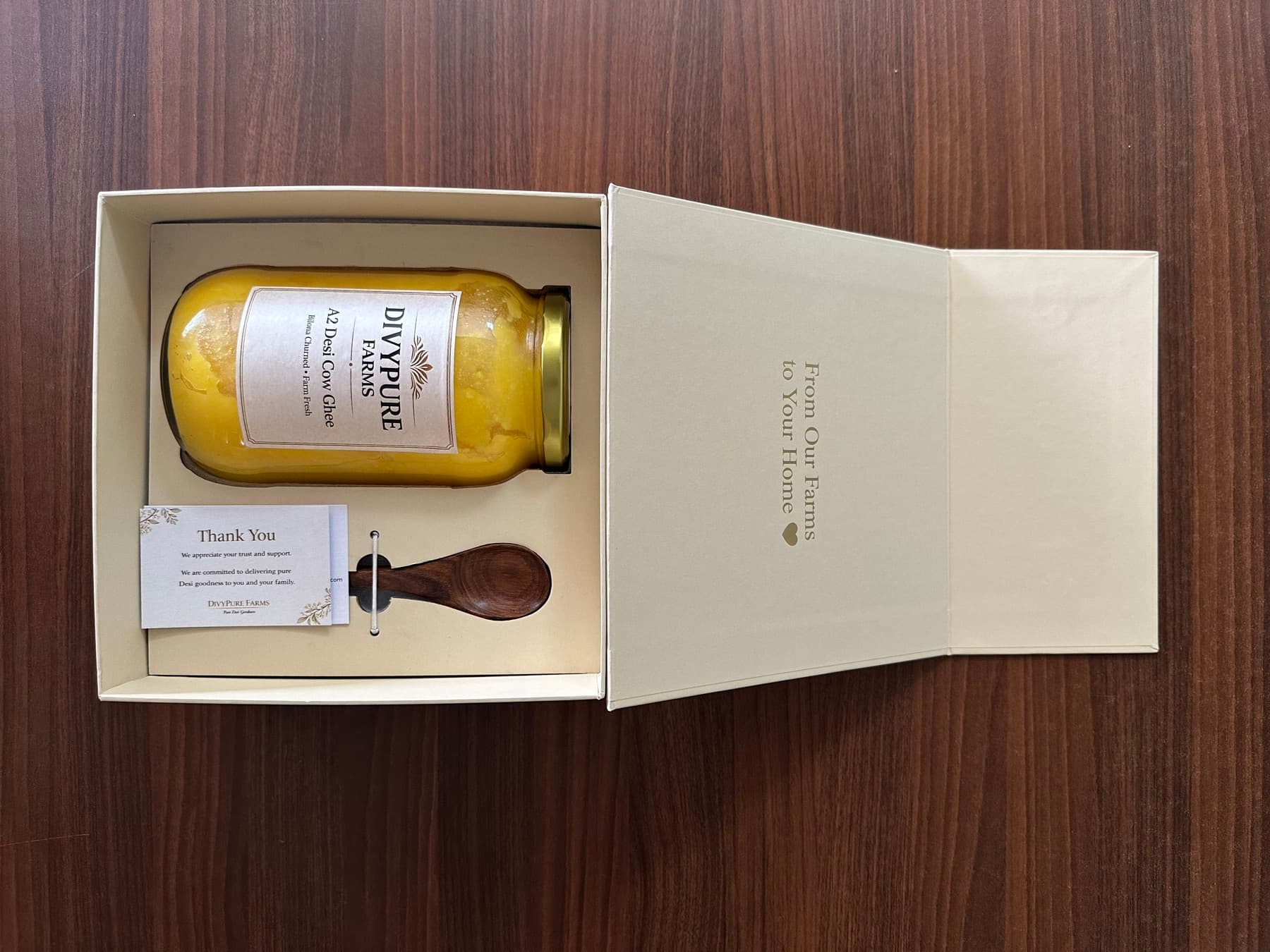 Open Divypure Farms gift box with A2 cow ghee jar, wooden spoon and thank-you card